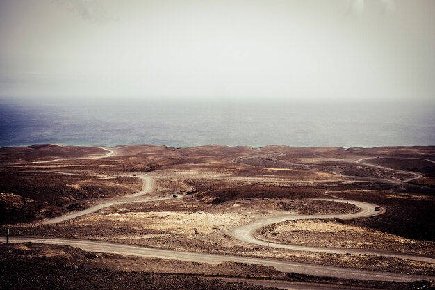 Photo beaucoup de routes pour voyager et découvrir le désert avec un véhicule préparé pour vivre des vacances différentes et insolites. plage et océan bleu à la fin d