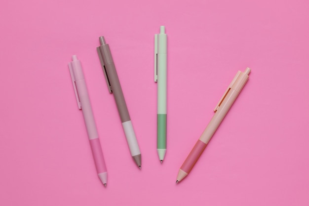 Beaucoup de stylos colorés en gros plan sur fond rose.