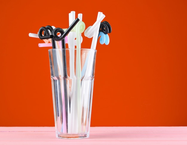 Photo beaucoup de tubes à cocktail dans un verre sur fond orange