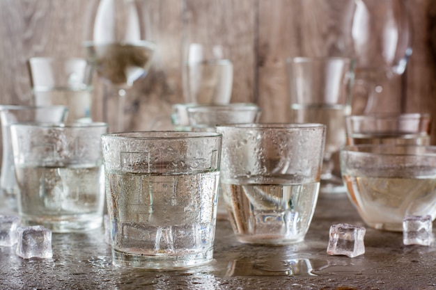 Beaucoup de verres d&#39;eau éclaboussés de gouttes et de morceaux de glace sur une table grise