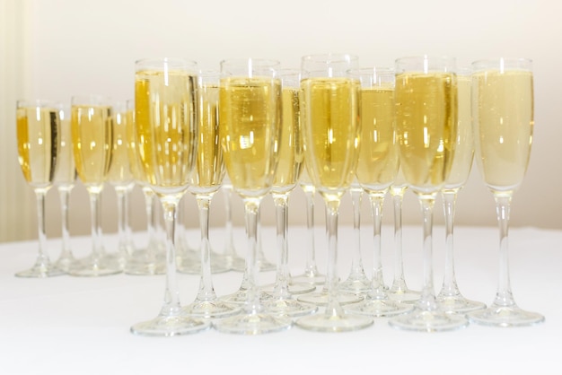 Beaucoup de verres flous avec du champagne sur la table de réception sur fond clair