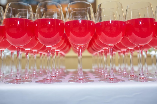 Beaucoup de verres flous avec du vin rouge sur la table de réception sur fond clair