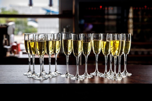 Beaucoup de verres à vin avec un délicieux champagne frais ou un vin blanc au bar ou à la restauration événementielle. Fond d'alcool.