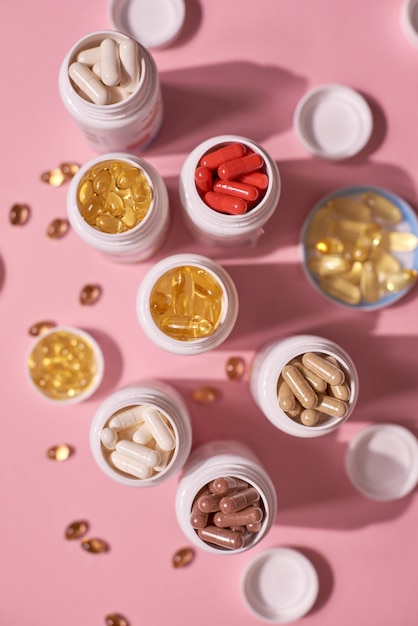 Beaucoup de vitamines de capsules de comprimés de couleur sur fond rose. Suppléments et médicaments bons pour la santé