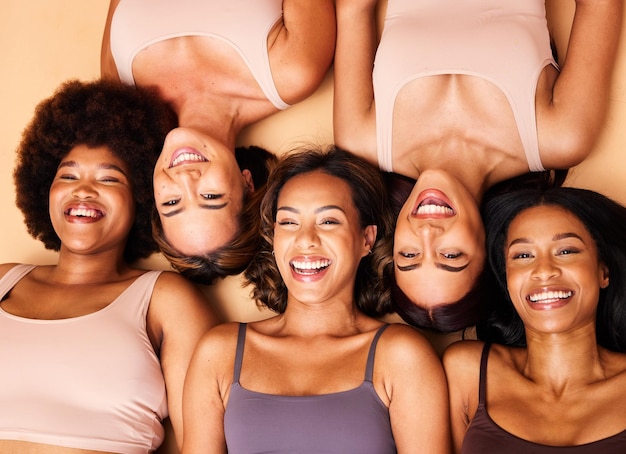 Beauté au-dessus et diversité heureuse des femmes avec le sourire pour les soins de la peau isolées dans un fond marron studio ensemble Portrait de soutien et groupe d'amis sur un sol pour les soins de la peau ou le maquillage du visage