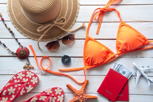 Photo beauté bikini orange et accessoires sur plancher en bois pour voyage en été