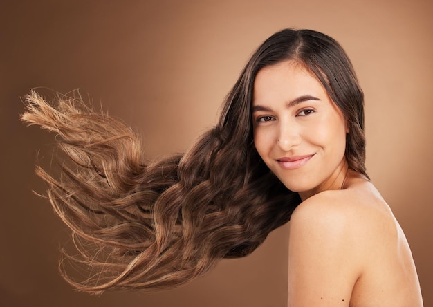 Beauté des cheveux et portrait de femme en studio pour le traitement de coiffure bien-être et la santé sur fond marron Sourire esthétique de salon et visage de fille heureuse avec des cosmétiques kératine et style naturel