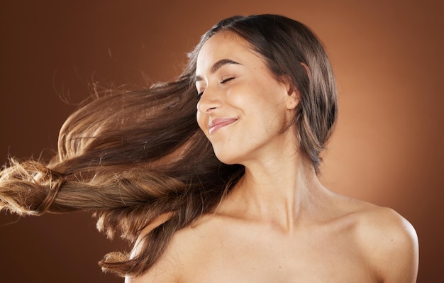 Beauté des cheveux et soins de la peau avec une femme modèle en studio sur fond marron pour un traitement naturel ou à la kératine Soins du visage et salon avec une jeune femme séduisante posant pour promouvoir un produit