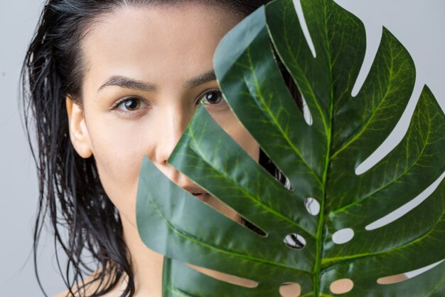 Beauté femme avec portrait de feuille de palmier vert naturel. Mode, beauté, maquillage, cosmétiques.