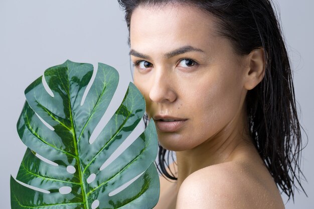 Beauté femme avec portrait de feuille de palmier vert naturel. Mode, beauté, maquillage, cosmétiques.