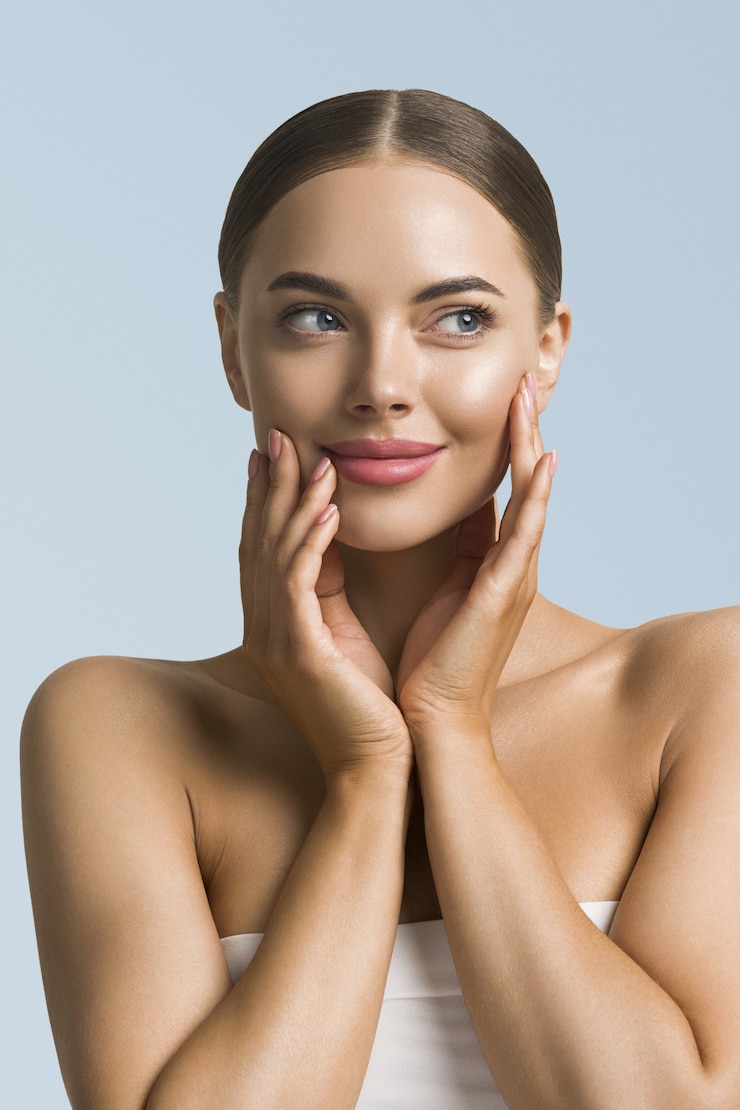 Photo beauté femme soins de la peau belle main féminine touchant le visage fille cosmétique modèle sur fond bleu