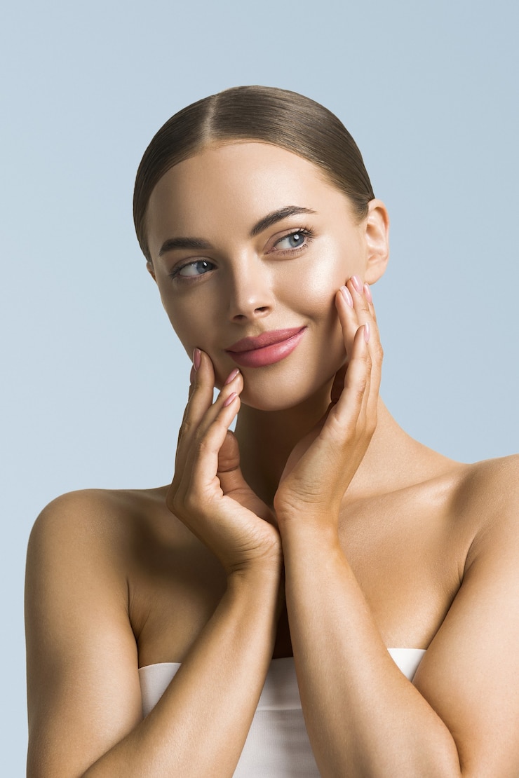 Photo beauté femme soins de la peau belle main féminine touchant le visage fille cosmétique modèle sur fond bleu