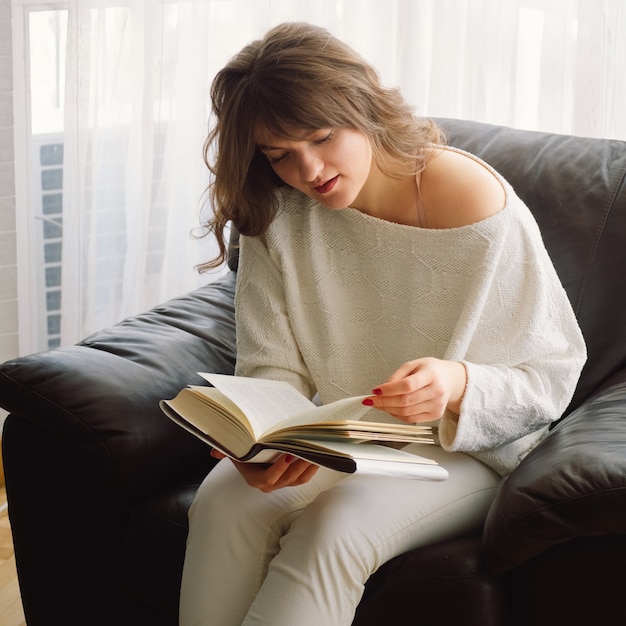 Beauté jeune femme lit un livre à la maison