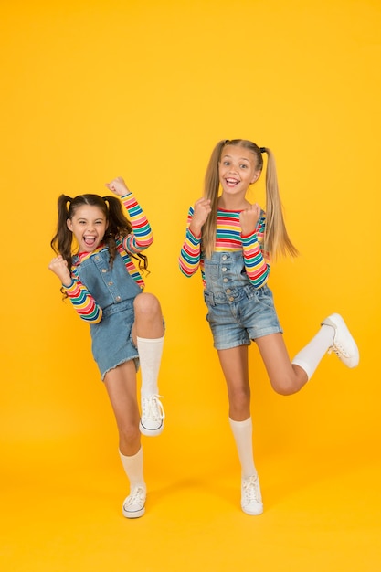 Beauté libre et énergique enfance heureuse vraie amitié meilleurs amis pour toujours petites soeurs s'amuser petites filles sauter fond jaune sentiment de liberté enfin vacances d'été