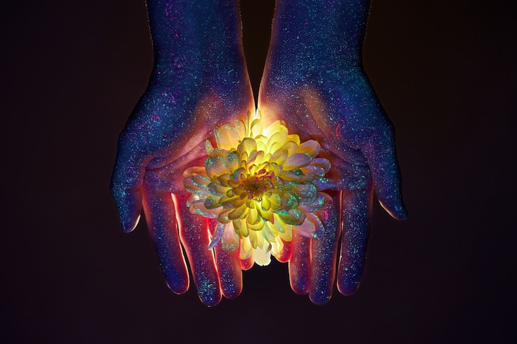 Photo beauté des mains d'une femme en lumière ultraviolette avec des fleurs dans les paumes