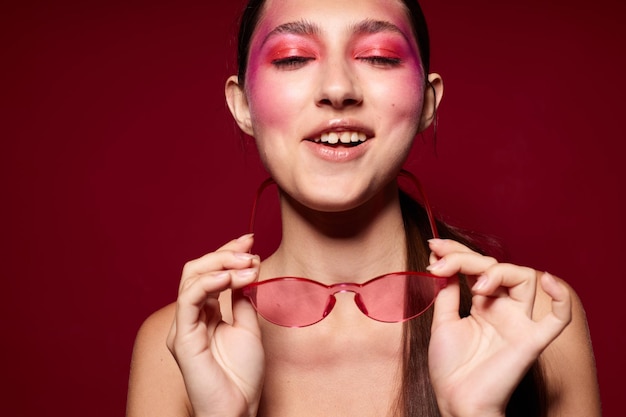 Beauté mode femme maquillage lumineux posant des émotions de mode lunettes de mode fond rose inchangé