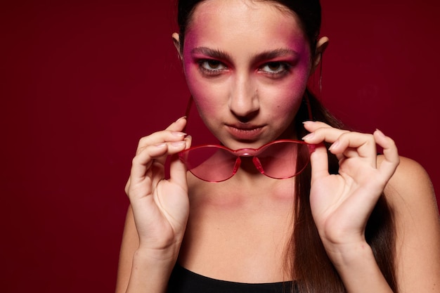 Beauté mode femme maquillage lumineux posant des émotions de mode lunettes de mode fond rose inchangé