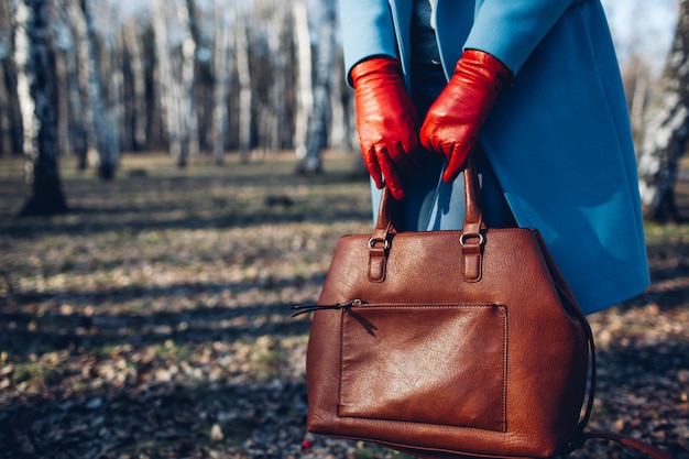 Beauté et mode. Élégante femme à la mode vêtue d&#39;une robe brillante tenant un sac à main marron