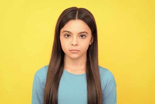 Beauté et mode mannequin femme joli look de jeune fille visage portrait d'enfant sur fond jaune exprimer des émotions enfant sérieux aux cheveux longs