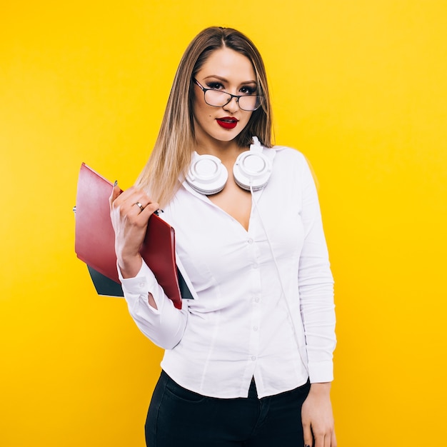 Beauté Et Mode. Professeur De Femme Aux Longs Cheveux Blonds. étudiante En Robe Sexy à La Mode Et Lunettes. Mannequin Pose Sur Le Mur Jaune. Look Et Style De Mode