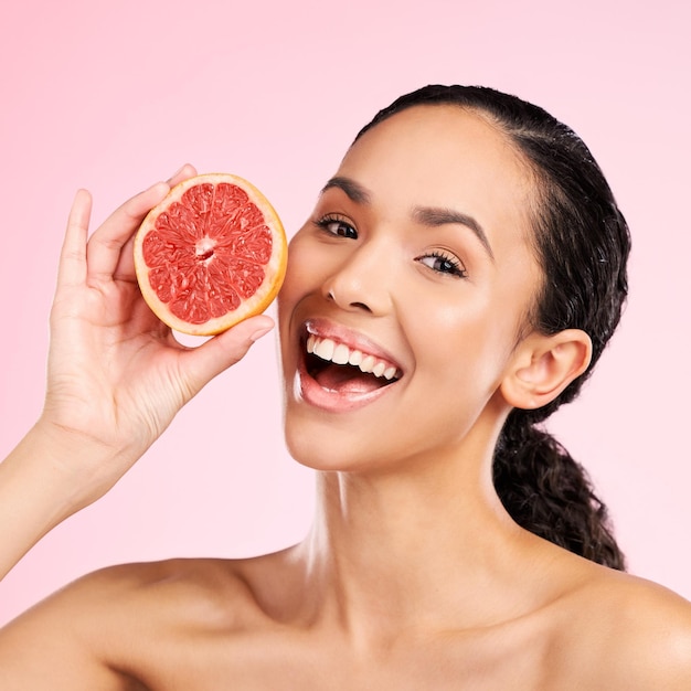 Beauté de pamplemousse et visage de femme heureuse avec dermatologie de soins de la peau ou éclat naturel Portrait d'un modèle féminin avec des fruits pour les cosmétiques à la vitamine c ou une alimentation saine pour la désintoxication sur fond de studio