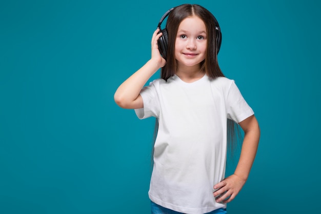 Beauté petite fille en tee-shirt et écouteurs aux cheveux longs