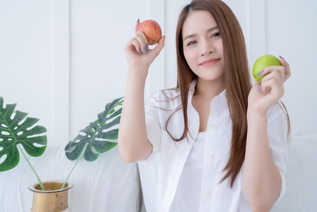 Beauté saine femme asiatique souriant avec la main tenir le concept d'idées d'aliments sains pomme rouge fraîche