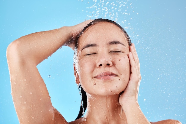 Beauté soins de la peau et cheveux femme sous la douche sur fond bleu soins capillaires et routine d'hygiène le matin Modèle dans les éclaboussures d'eau nettoyant les cheveux et le visage avec de l'eau courante pour un style de vie frais