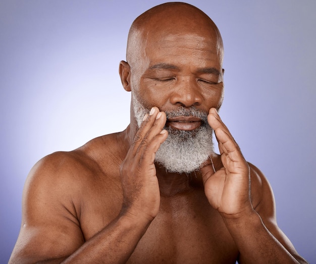 Beauté de soins de la peau et homme noir senior avec dermatologie nettoyant le bien-être et la paix cosmétique sur fond de studio violet Spa cosmétiques corps de retraite et visage d'un modèle africain âgé propre