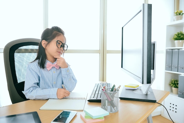 beauté souriante fille d'affaires écrivant un enregistrement sur le livre et regardant l'ordinateur de travail pensant la planification future de l'entreprise au bureau.