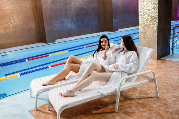 Beauté spa concept de mode de vie sain Belles jeunes filles en peignoir se détendre au spa de luxe sur une chaise longue près de la piscine Thème bien-être