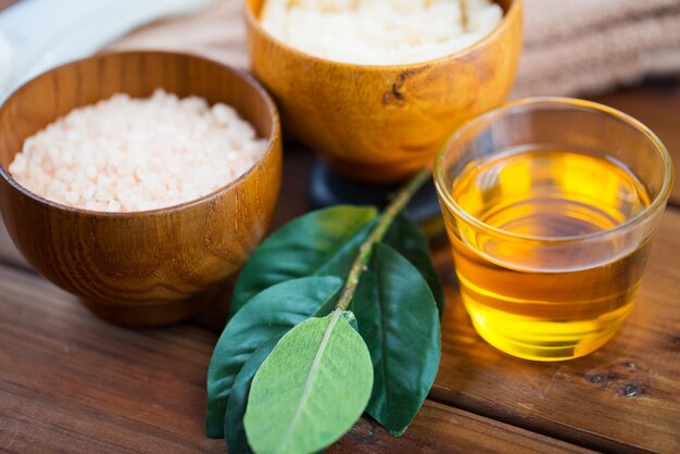 beauté, spa, soins du corps et concept de cosmétiques naturels - gros plan de miel en verre, avec du sel rose et des feuilles sur une table en bois