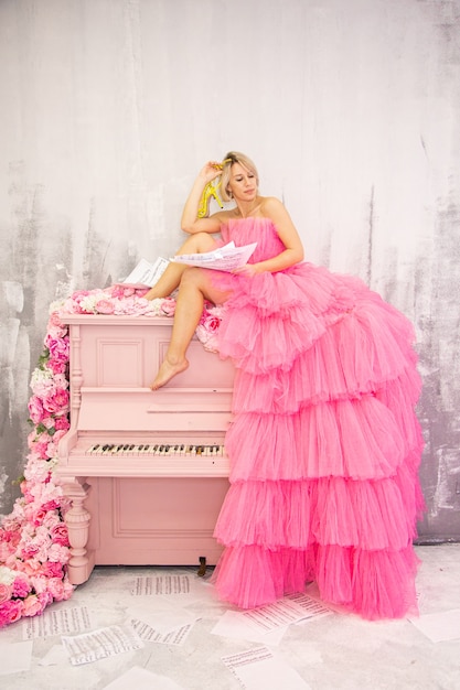 Beautifu lblonde femme posant sur piano rose. Photo de haute qualité