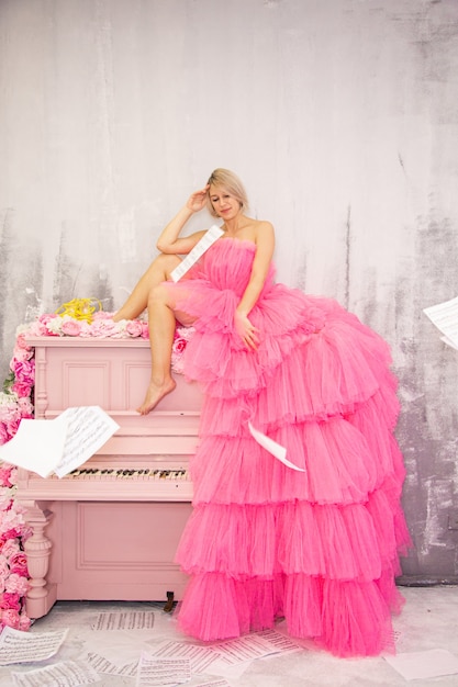 Beautifu lblonde femme posant sur piano rose. Photo de haute qualité