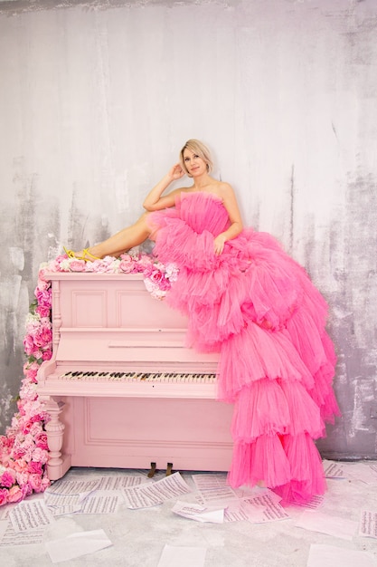 Photo beautifu lblonde femme posant sur piano rose