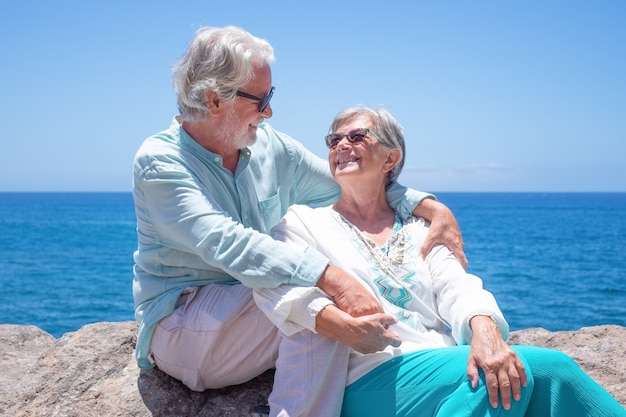 Beautiful senior couple hugging at the sea profitant de la lumière du soleil Deux retraités se regardant