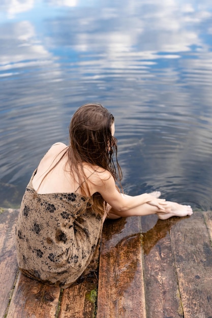 Beauty Girl Outdoors profitant de la nature Beautiful Teenage Model girl in dress sitting on the river bank at sunset