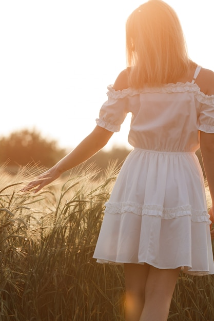 Beauty Girl Outdoors profiter de la nature. Belle adolescente modèle fille en robe blanche en cours d'exécution sur le champ de printemps, la lumière du soleil.