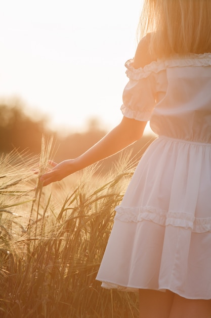 Beauty Girl Outdoors profiter de la nature. Belle adolescente modèle fille en robe blanche en cours d'exécution sur le champ de printemps, la lumière du soleil.