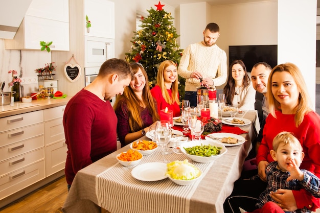 Beaux amis et parents attrayants et bien habillés félicitant tout en passant ensemble l'événement de la fête d'hiver dans une maison décorée.