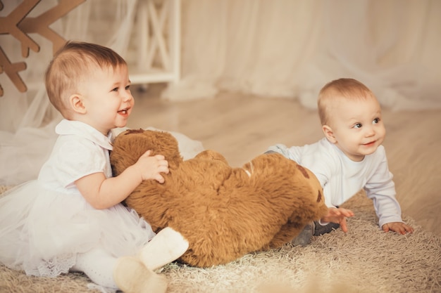 Beaux bébés enfants avec un ours en peluche brun doux à l'intérieur avec des décorations de Noël