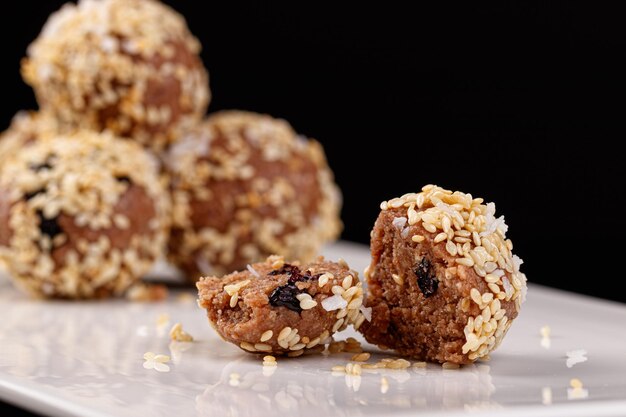 Beaux bonbons aux graines de sésame sur une plaque blanche sur fond noir