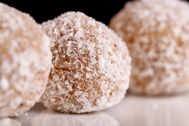 Beaux bonbons à la noix de coco sur une plaque blanche sur fond noir