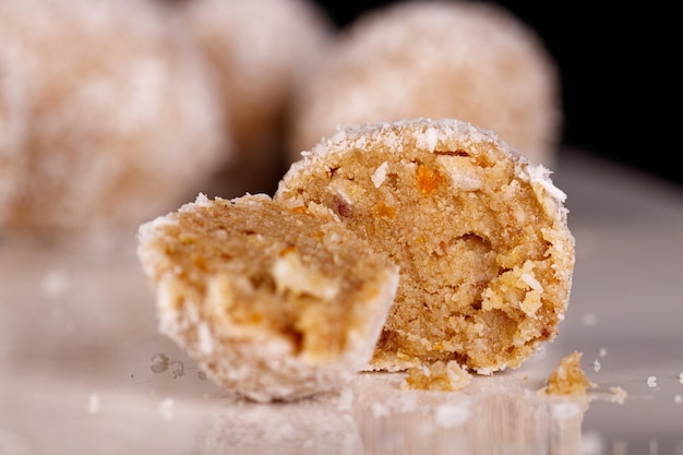 Beaux bonbons à la noix de coco sur une plaque blanche sur fond noir