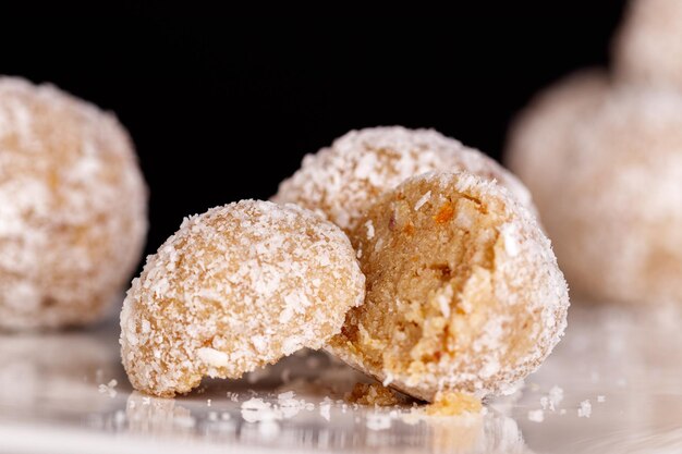 Beaux bonbons à la noix de coco sur une plaque blanche sur fond noir