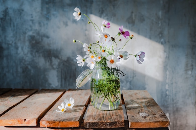 Beaux bouquets de fleurs sauvages sur une table en bois sur un mur de béton froid.