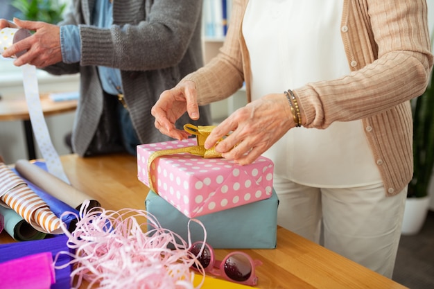 De beaux cadeaux. Gros plan de deux coffrets cadeaux debout sur la table devant une femme âgée agréable