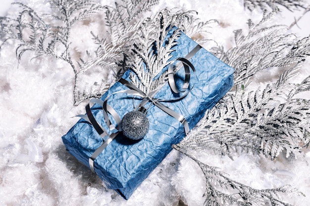 Photo beaux cadeaux de nouvel an faits à la main de couleur bleu argenté. carte de noël avec fond bleu et argent. décoration de noël avec pin, sapin et coffrets cadeaux. fermer,