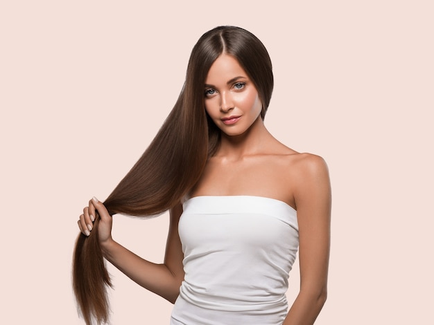 Beaux cheveux lisses longue brune coiffure femme peau saine. Fond de couleur. Rose