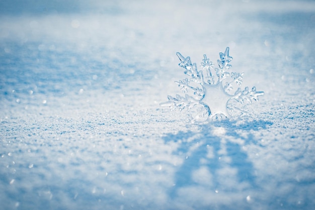 De beaux cristaux de glace se trouvent dans la neige et scintillent au soleil bokeh sur fond bleu